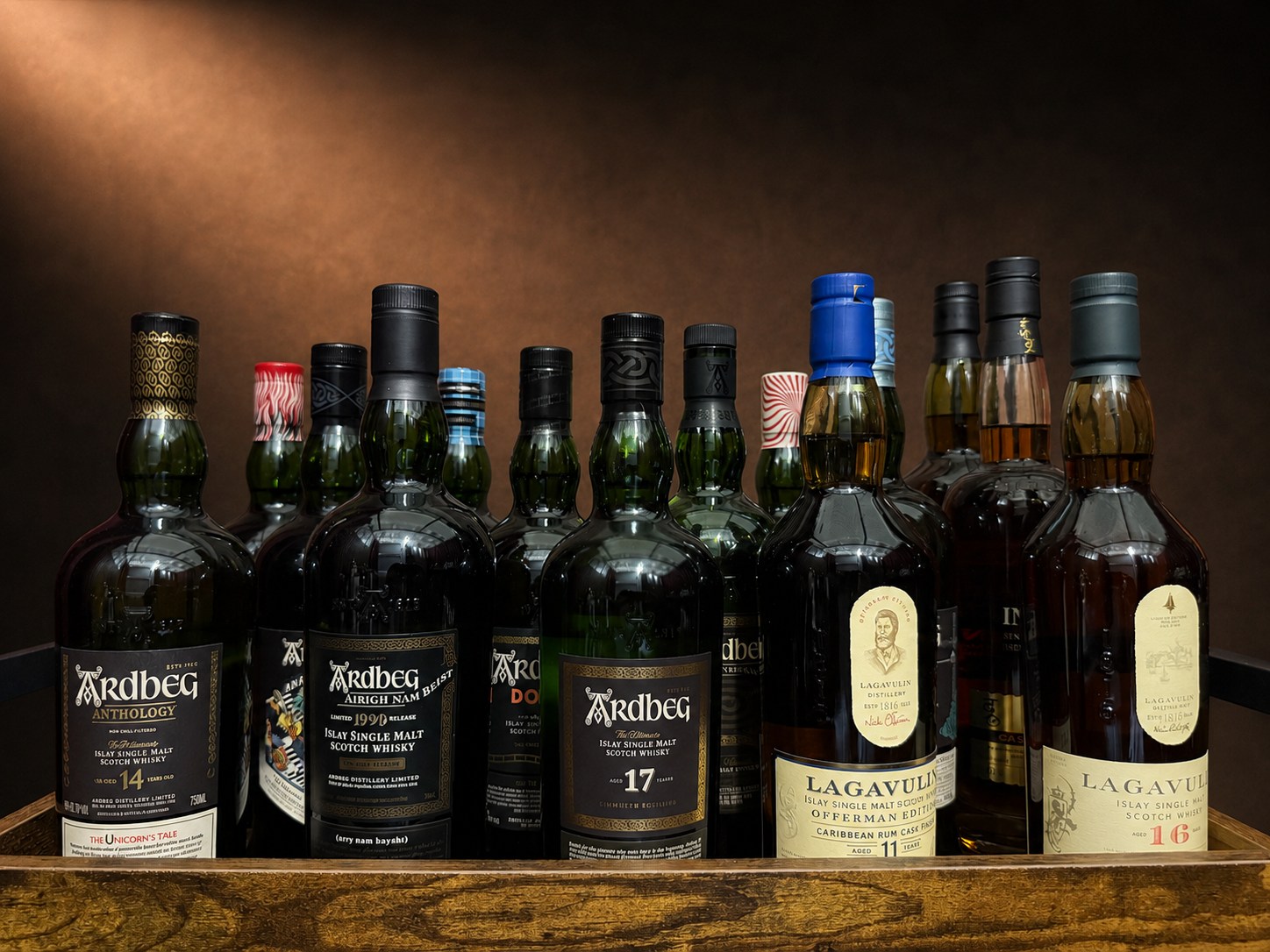 Eleven Islay whisky bottles on a dark wooden shelf, mostly Ardbeg alongside several Lagavulin bottles including the Offerman Edition