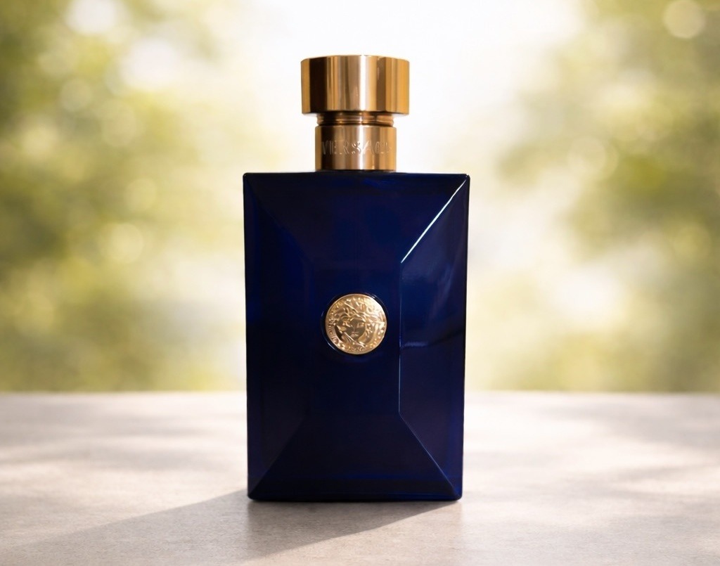Versace Dylan Blue bottle, deep navy blue glass with gold Medusa medallion, outdoor bokeh background