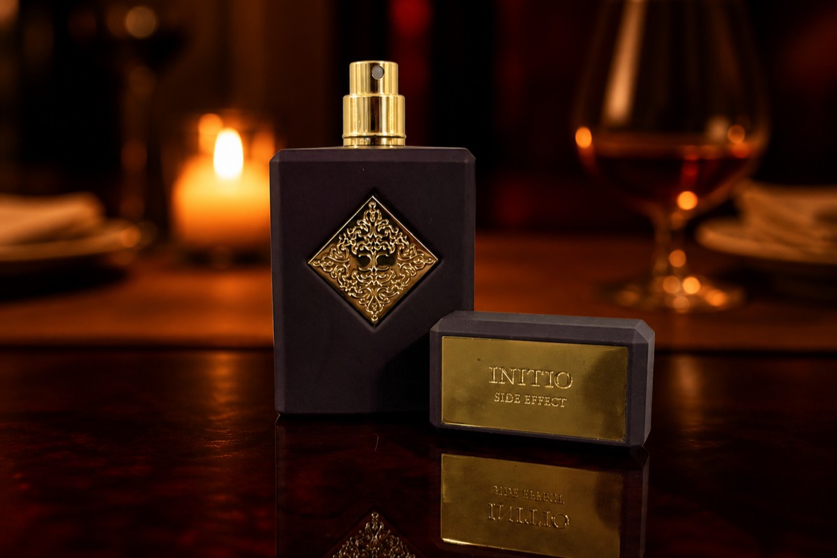 Initio Side Effect bottle and box on a dark table, a moodier candlelit restaurant scene blurred behind it with a glass of rum